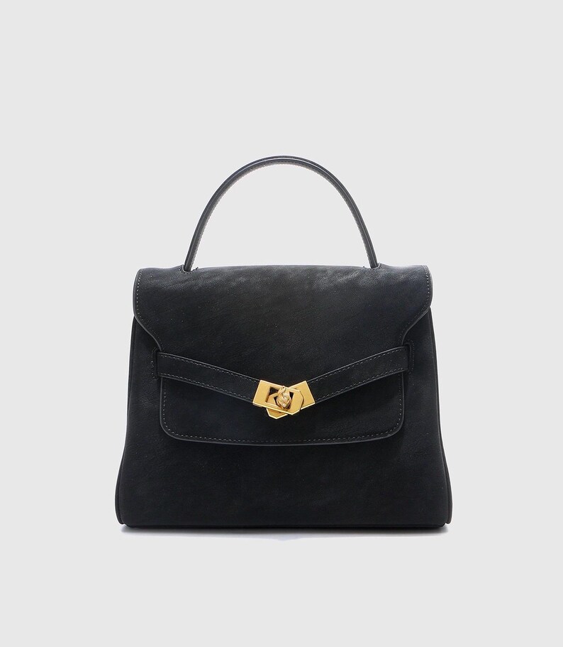 May include: A black handbag with a top handle and a flap closure. The bag features a gold-colored clasp and a small front pocket. The leather bag has a structured design and a minimalist aesthetic.