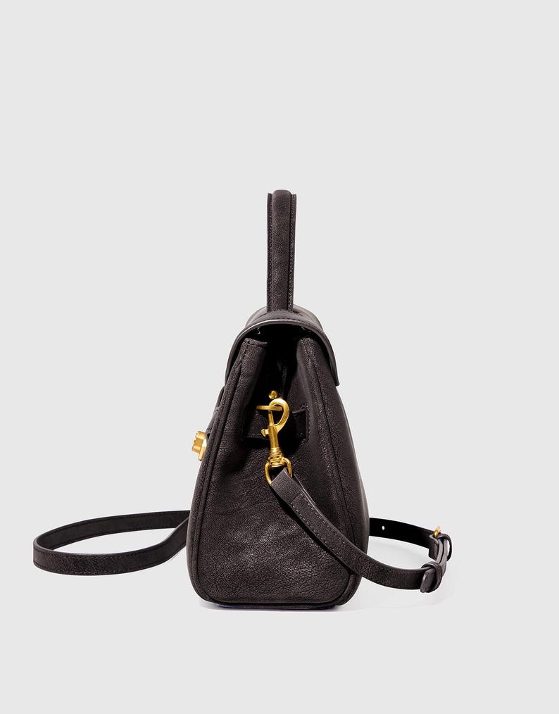 May include: A dark brown leather handbag with a top handle and a detachable shoulder strap. The bag features gold-colored hardware, including a clasp closure and strap attachments. The bag is designed with a structured shape.