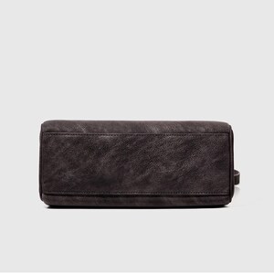 May include: A dark gray handbag with a rectangular shape. The bag has a textured surface and a small strap on the side. The bag appears to be made of leather or a similar material.