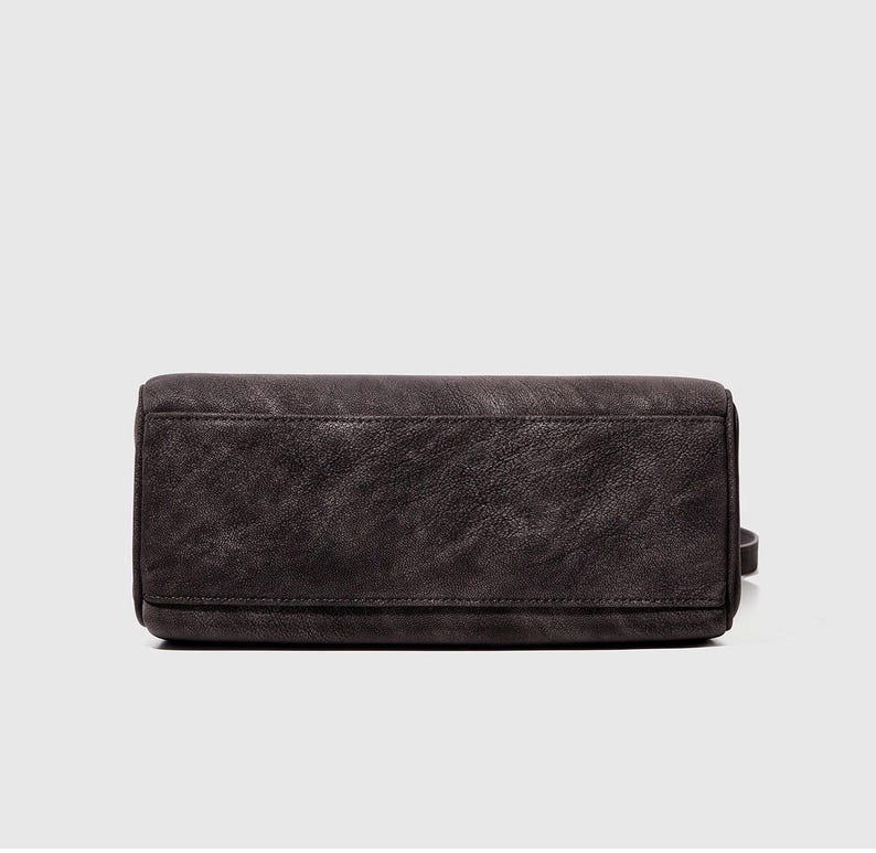 May include: A dark gray handbag with a rectangular shape. The bag has a textured surface and a small strap on the side. The bag appears to be made of leather or a similar material.