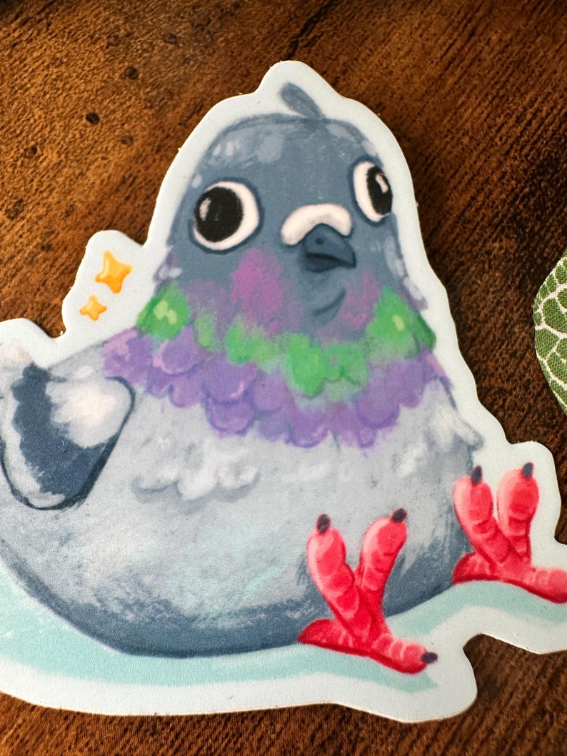 May include: A sticker featuring a cartoon pigeon with a blue-grey body, purple and green neck feathers, and bright red feet. The pigeon has large, expressive eyes and is surrounded by a white border with two small yellow stars.