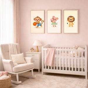 Puede incluir: Tres impresiones enmarcadas de arte de guardería con animales de dibujos animados: un mono con una pelota de baloncesto, un cerdo con una flor y un león. Las impresiones se exhiben sobre una cuna blanca y una mecedora en una guardería de temática rosa.