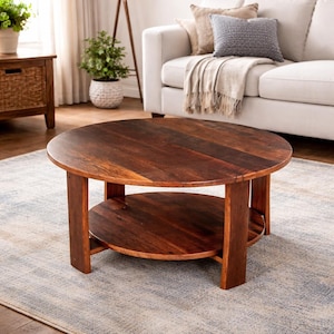 May include: A round, dark brown wooden coffee table with a lower shelf. The table has a natural wood grain finish and is supported by four sturdy legs. The table is approximately 36 inches in diameter.