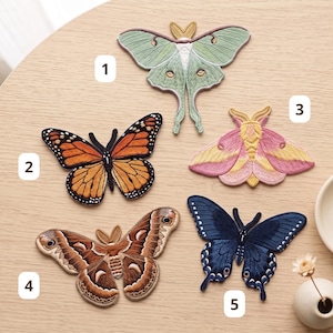 May include: Five embroidered moth and butterfly patches labeled 1 through 5. Patch 1 is a pale green luna moth, 2 is an orange and black monarch butterfly, 3 is a pink and yellow moth, 4 is a brown patterned moth, and 5 is a dark blue butterfly.