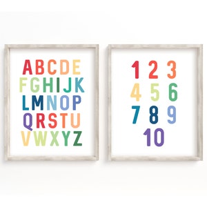 May include: Two framed prints with a white background. One print displays the alphabet in rainbow colors, the other displays the numbers 1-10 in rainbow colors. The frames are light wood.