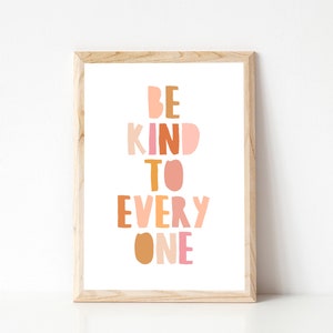 May include: A framed print with the text "BE KIND TO EVERY ONE" in a colorful, layered font style. The letters are in shades of pink, orange, and brown.