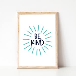 May include: A framed print with a white background and a blue and black graphic that says "Be Kind" surrounded by blue sun rays.