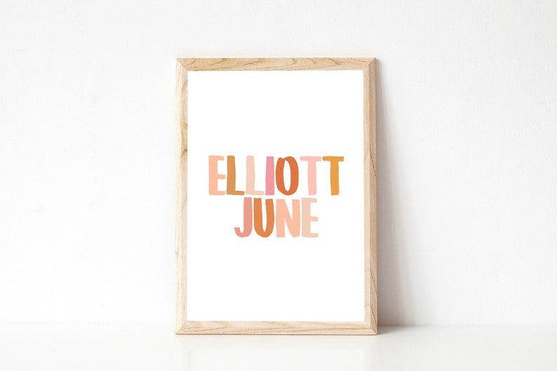 K&ouml;nnte beinhalten: Ein gerahmter Druck mit dem Namen "Elliott June" in bunten, &uuml;bereinanderliegenden Buchstaben. Die Buchstaben sind in Rosa-, Orange- und Gelbt&ouml;nen gehalten.