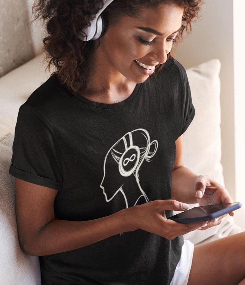 May include: Black t-shirt featuring a white graphic of a person's profile wearing headphones with an infinity symbol. The person is holding a smartphone. The t-shirt is a crew neck style.