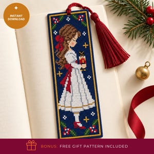 May include: A rectangular cross-stitch bookmark on a dark blue background featuring a girl with brown hair in a white dress holding a nutcracker. The design includes red bows, green holly leaves, and gold stars, finished with a red tassel at the top.