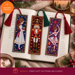 May include: Three rectangular cross-stitch bookmarks featuring holiday designs: a girl in a white dress, a nutcracker soldier, and a ballerina. Each bookmark has a colored tassel attached to the top, including red and dark green thread accents.