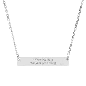 Può includere: Collana color argento con pendente rettangolare. Il pendente reca l'incisione "I Trust My Data Not Your Gut Feeling". La catena è a maglie sottili.