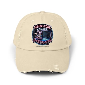 May include: A beige distressed baseball cap with a colourful graphic. The graphic features the text "COFFEE, CODE, & CHAOS" with a laptop, coffee cup, and the word "CODE". The phrase "Strength & Stilettos" is also present.