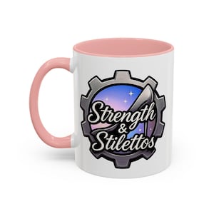 May include: White ceramic mug with a pink interior and handle. The mug features a graphic of a high-heeled shoe inside a gear, with the words "Strength & Stilettos" in a stylized font. The background is a gradient of purple and blue.