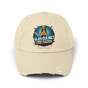 May include: A distressed beige baseball cap with a graphic that reads "GLASS CEILING? I PREFER TO CALCULATE LOAD CAPACITY." The graphic features a woman in a hard hat and safety glasses. The hat has a curved brim and adjustable strap.