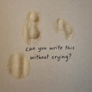 Puede incluir: Superficie beige claro con tres manchas húmedas y el texto escrito a mano: "can you write this without crying?" El texto está en tinta negra. Las manchas húmedas son de forma irregular y parecen ser de color claro.