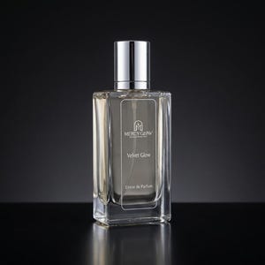 May include: A rectangular glass perfume bottle with a silver cap. The bottle has a clear liquid inside and features the text "MERCY GLOW" and "Velvet Glow" in white. The words "Extrait de Parfum" are also visible.