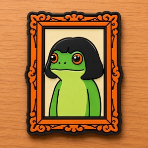May include: A whimsical, framed portrait featuring a green frog with large orange eyes and a black bob haircut. The frame is orange with ornate black detailing. The frog is set against a cream-colored background.