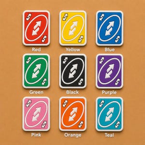 May include: Nine colorful Uno reverse cards arranged on a brown surface. Each card features a white border, a central white arrow design, and a color-coded background: red, yellow, blue, green, black, purple, pink, orange, and teal. The color names are printed below each card.