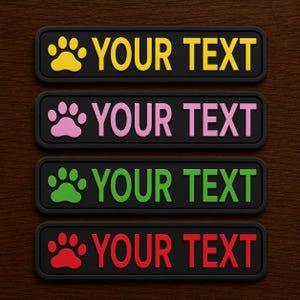 May include: Four rectangular black patches with rounded corners, each featuring a raised paw print icon on the left and the text YOUR TEXT in a bold, sans-serif font. The paw prints and text appear in yellow, pink, green, and red respectively.