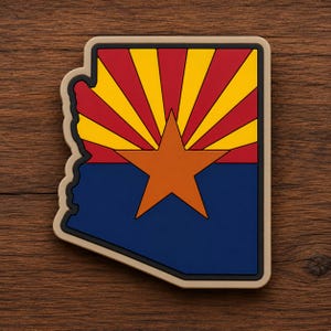 May include: A die-cut sticker shaped like the state of Arizona featuring the state flag design. The top half displays alternating red and yellow sun rays, while the bottom half is solid blue with a large copper-colored star centered in the middle.