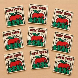 May include: Nine square stickers with a red apple, green figures, and the text "NEW YORK" in a black outline. The apple has a green leaf and is surrounded by white rays. The figures are raising their arms.