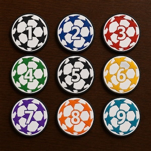 May include: Nine circular patches featuring a white soccer ball pattern with colored star accents. Each patch displays a unique number from one to nine in the center. The colors include black, blue, red, green, yellow, purple, orange, and teal.