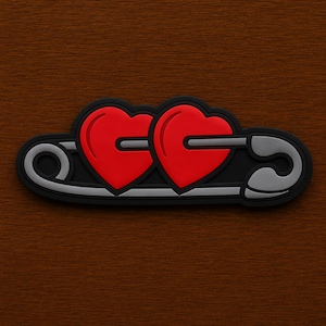 May include: A black and gray safety pin design with two red hearts. The hearts are side-by-side, and the pin is a stylized representation of a safety pin. The design is set against a brown wooden background.