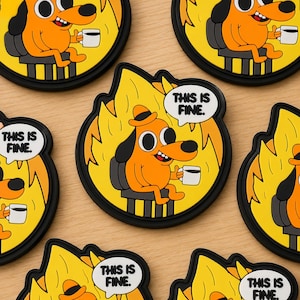 May include: A collection of round coasters featuring a cartoon dog sitting in a burning room, holding a coffee cup. The dog is orange with a black hat and backpack. Each coaster has the text "THIS IS FINE." in a speech bubble.