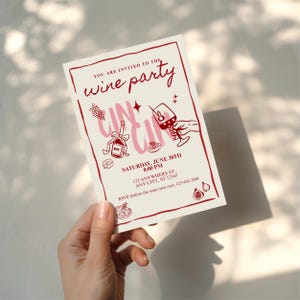 Op de afbeelding: Een cr&egrave;mekleurige wijnfeestuitnodiging met rode tekst en illustraties. De uitnodiging bevat de tekst "YOU ARE INVITED TO THE wine party" en evenementdetails. De illustraties omvatten een wijnfles, druiven en een wijnglas.