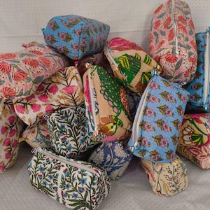 Peut inclure: Une collection de trousses rectangulaires en tissu matelassé présentant divers motifs floraux imprimés en bloc dans des tons de bleu, rose, vert et crème. Chaque trousse est dotée d'une fermeture éclair et d'un textile en coton piqué.