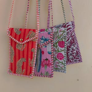 Pode incluir: Quatro bolsas tiracolo acolchoadas com alças longas listradas e fechos de pressão dourados. As bolsas apresentam vários padrões, incluindo laranja com guepardos, rosa com cactos, branco com flores rosas e branco com estampas florais roxas.