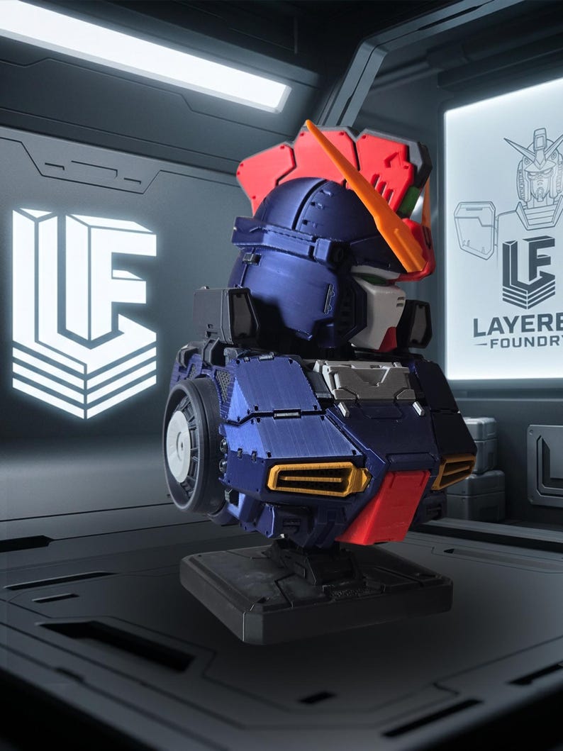 May include: A detailed model of a robot head, featuring a color scheme of navy blue, red, and white. The model has a futuristic design with visible mechanical details. The logo "LF" is displayed on the left, and the text "LAYERED - FOUNDRY" is on the right.