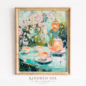 Könnte beinhalten: Ein impressionistisches Gemälde einer Tee-Szene mit einer pfirsichfarbenen Teekanne, Tassen und einer hängenden Laterne. Die Szene spielt auf einem türkisfarbenen Tisch mit floralem Hintergrund. Das Kunstwerk ist in einem goldfarbenen Rahmen gerahmt. Der Text "KINDRED SOL fine art prints" befindet sich unten.