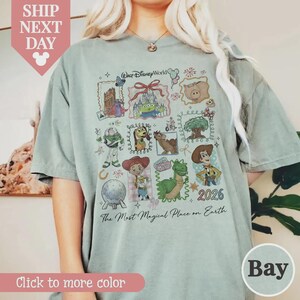 Puede incluir: Una camiseta verde claro con un gr&aacute;fico colorido de personajes y atracciones de Disney. El dise&ntilde;o incluye el texto "Walt Disney World" y "The Most Magical Place on Earth". El a&ntilde;o "2026" tambi&eacute;n es visible.