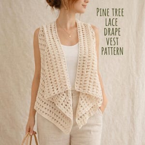 May include: A cream-colored, open-front vest with a lace pattern. The vest is sleeveless and drapes elegantly. The text "PINE TREE LACE DRAPE VEST PATTERN" is visible on the right side of the image. The vest is likely handmade.