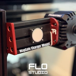 May include: Black and red MagSafe charger mount with the text "MagSafe Charger Mount" and "FLO STUDIO". The mount is attached to a black metal frame. The charger has a circular, light-colored center.