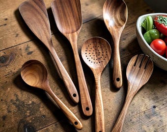 Juego de utensilios de cocina de madera natural con soporte: espátula, cuchara, tenedor y utensilios para mezclar.