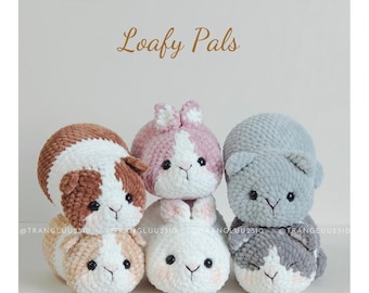 May include: Six crocheted plush animals arranged in pairs, labeled Loafy Pals and English Pattern. The set includes brown and white, pink and white, and gray and white creatures with black eyes and stitched noses, crafted from soft yarn.