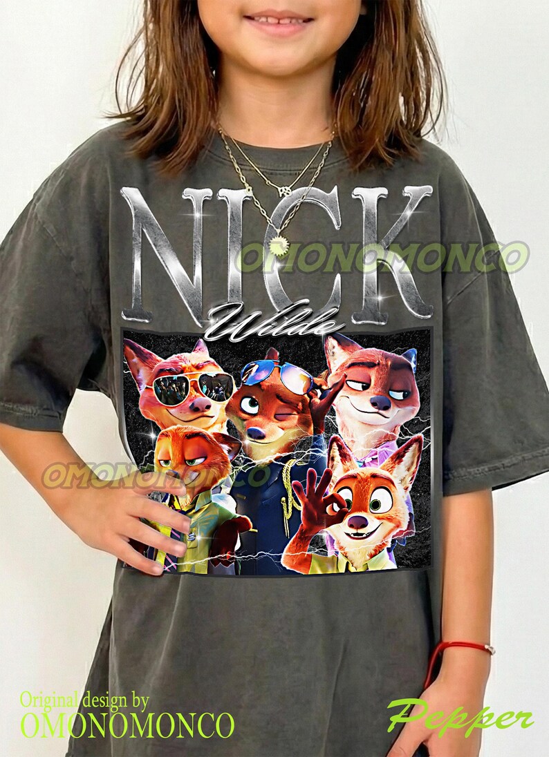 May include: Dark gray t-shirt featuring a graphic of Nick Wilde from Zootopia. The design includes the name "NICK Wilde" in silver lettering above a group of cartoon foxes. The shirt has a vintage, worn look.