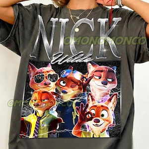 May include: Dark gray t-shirt featuring a graphic of Nick Wilde from Zootopia. The design includes the name "Nick Wilde" in silver lettering above a collage of cartoon foxes. The shirt has the text "OMONOMONCO" and "Pepper".