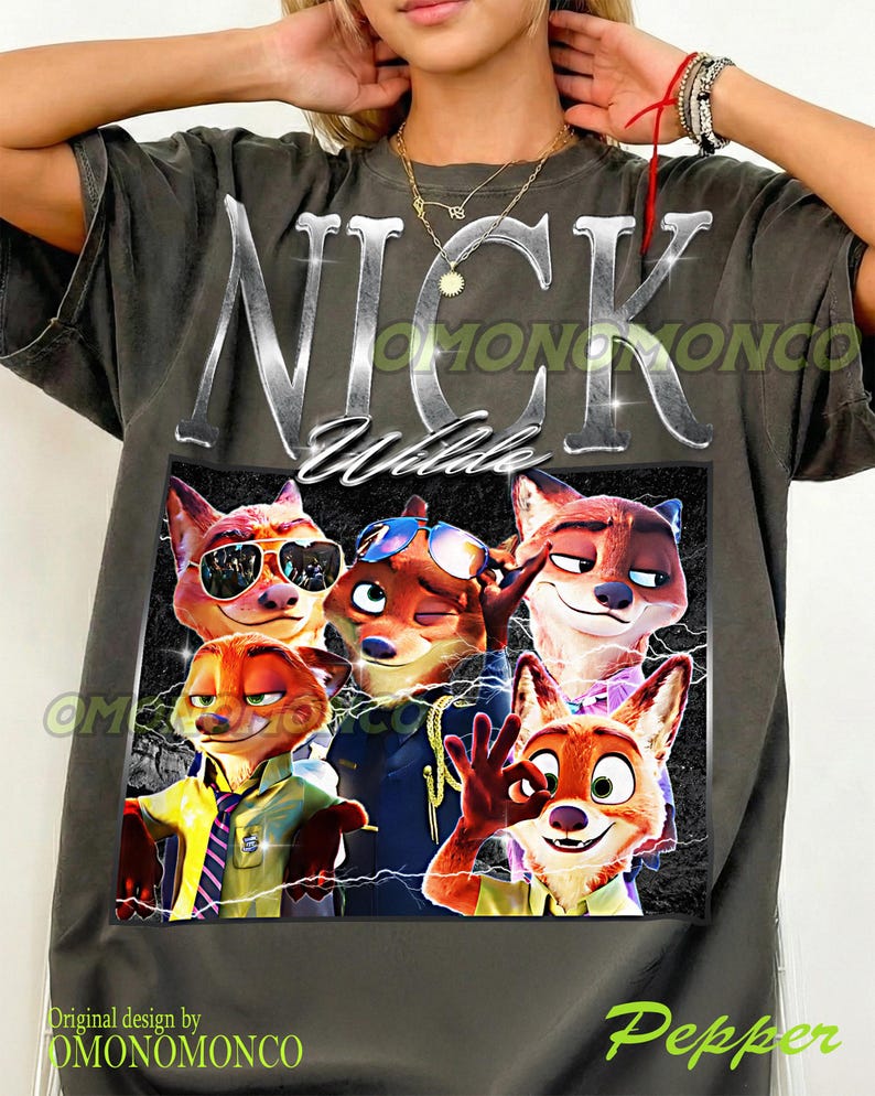 May include: Dark gray t-shirt featuring a graphic of Nick Wilde from Zootopia. The design includes the name "Nick Wilde" in silver lettering above a collage of cartoon foxes. The shirt has the text "OMONOMONCO" and "Pepper".