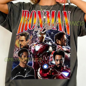 Peut inclure: Un t-shirt gris anthracite avec une impression graphique d'Iron Man et Tony Stark. Le motif inclut le texte IRON MAN et Tony Stark, avec plusieurs images du personnage en costume et sans, entouré d'effets d'éclairs et de nébuleuses spatiales.