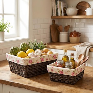 May include: Two woven brown baskets with floral fabric lining. One basket holds artichokes, lemons, garlic, and potatoes. The other basket contains olive oil bottles, spices, and wooden spoons. The baskets sit on a wooden countertop.