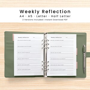 May include: An open sage green six-ring binder containing white paper inserts with the text Weekly Reflection. The pages feature lined sections with prompts such as What emotion defined this week and What did I accomplish this week. A silver pen is attached to the side.