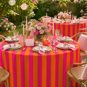 May include: A round table covered in a vibrant hot pink and orange vertical striped tablecloth, set with white plates, light pink napkins, clear glassware, silver cutlery, and a central floral arrangement with a sign reading Good Vibes.