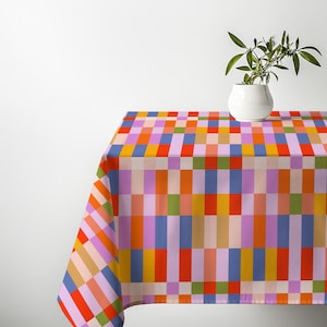 May include: A rectangular tablecloth featuring a vibrant grid pattern of vertical and horizontal stripes in shades of light pink, orange, red, blue, yellow, and green. The fabric displays a consistent woven texture throughout the colorful design.
