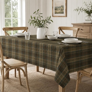 May include: A rectangular dining table covered with a dark olive green and navy blue plaid tablecloth. The table is set with white ceramic bowls, clear glass tumblers, and silver forks. A white ceramic pitcher with green foliage sits centrally.