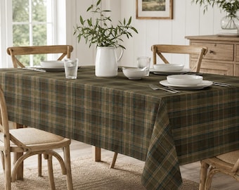 May include: A rectangular dining table covered with a dark olive green and navy blue plaid tablecloth. The table is set with white ceramic bowls, clear glass tumblers, and silver forks. A white ceramic pitcher with green foliage sits centrally.