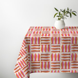 May include: A rectangular tablecloth featuring a repeating pattern of stylized fish in shades of orange and pink on a cream background. The fish are arranged in alternating horizontal and vertical rows across the fabric surface.